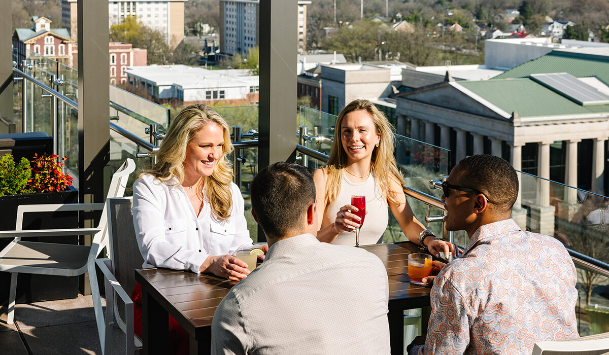 2 Men and 2 Women having drinks on rooftop restaurant